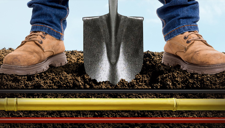 Worker with shovel poised to strike underground utility lines